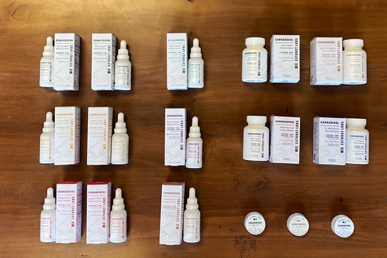 a birds eye view of Extract labs new tincture, isolate and capsule packaging on a wood background