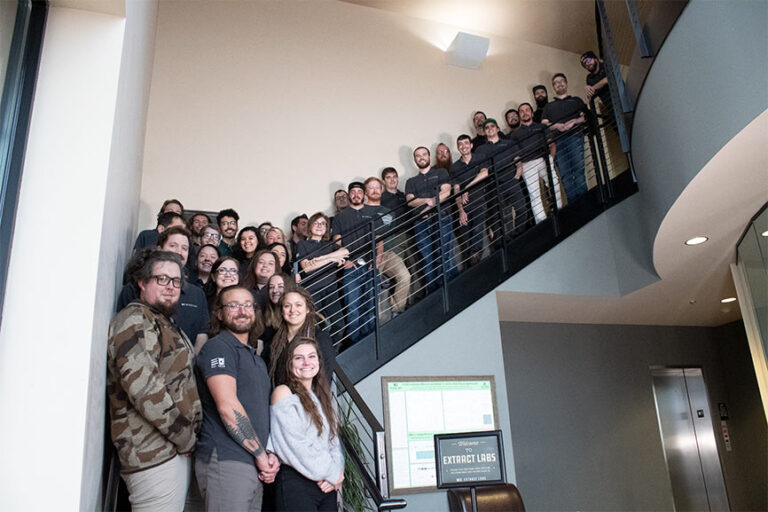a group photo of all Extract Labs employees standing on a staircase at their new Lafayette location on grand opening day