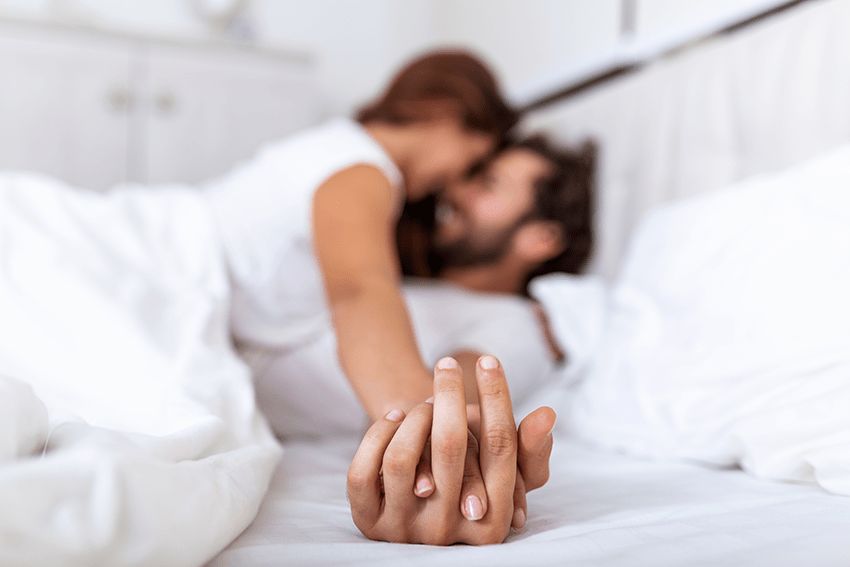 Can CBD Enhance Orgasms? CBD & Sex | image of a couple holding hands in bed