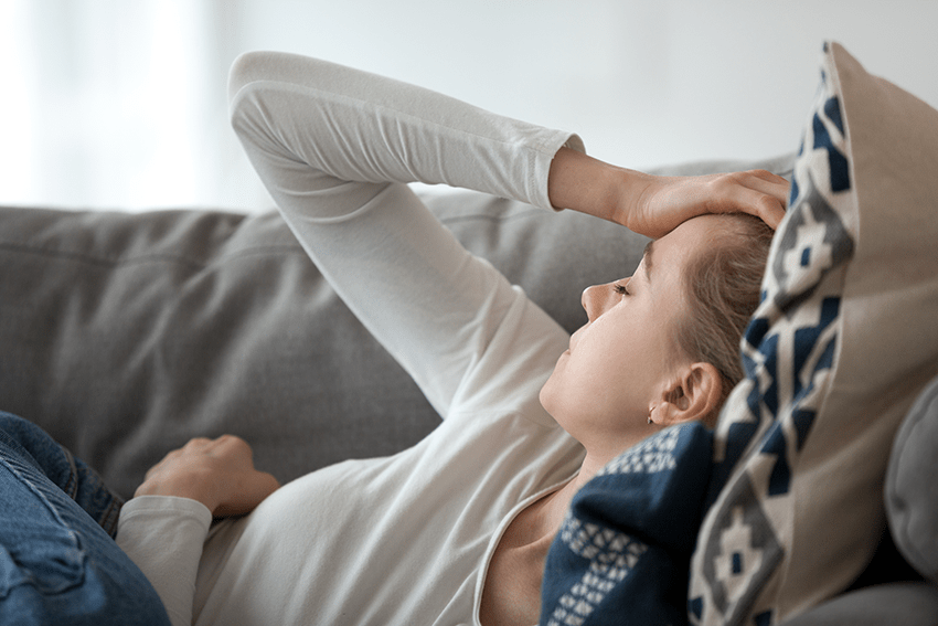 women's hisotry month blog | cbd muscle cream for womens wellness | photo of woman laying on couch with headache