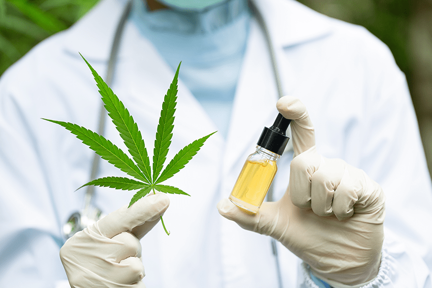 image of a scientist in a lab coat holding a hemp leaf and a small tincture oil bottle for the blog about 5 Misconceptions About CBD Oil Debunked