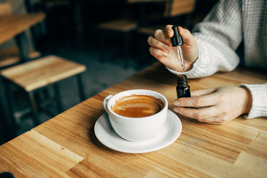 image of a CBD oil tincture being added into coffee for the blog about 6 Possible Ways You Can Use CBD Oil Tinctures