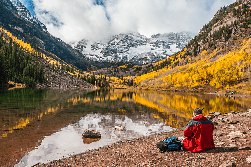 10 Best Hikes In Colorado & How CBD Can Help You Achieve Your Goals 2 image of a man taking a break in front of a lake and mountains for the blog about 10 Best Hikes In Colorado & How CBD Can Help You Achieve Your Goals