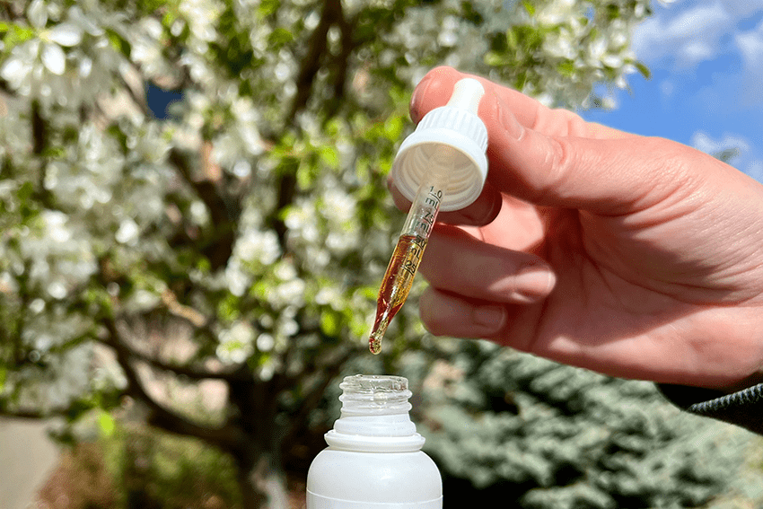 image of an oil tincture dropper over the bottle for blog about Does CBD Potency Matter? A Deep Dive Into the World of CBD Products | CBD Potency | CBD Products | HIgh potency CBD | high potency CBD Gummies | high potency CBD oil