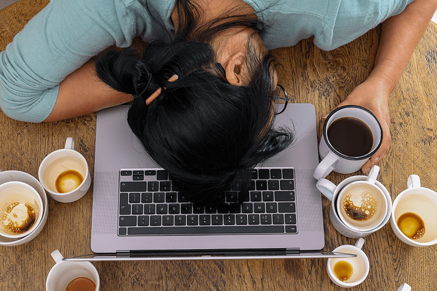 image of a woman with her head down on her laptop surrounded by empty coffee mugs for blog about Does CBD Potency Matter? A Deep Dive Into the World of CBD Products | CBD Potency | CBD Products | HIgh potency CBD | high potency CBD Gummies | high potency CBD oil