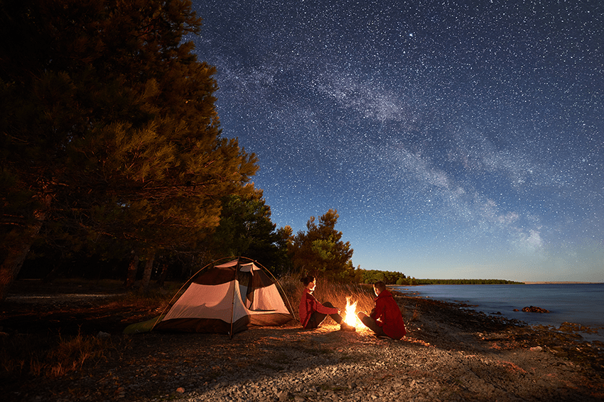 image of nighttime camping in front of a fire with a sky full of starts for blog about Elevate Your Game: CBD Products for Athlete Performance | Best workout supplement for men | best recovery supplement | athletic performance