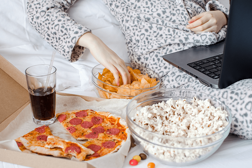 image of woman snacking in bed while on laptop for blog about Harnessing Hemp for Healthy Weight Loss | cbd for weight loss | how to loose weight