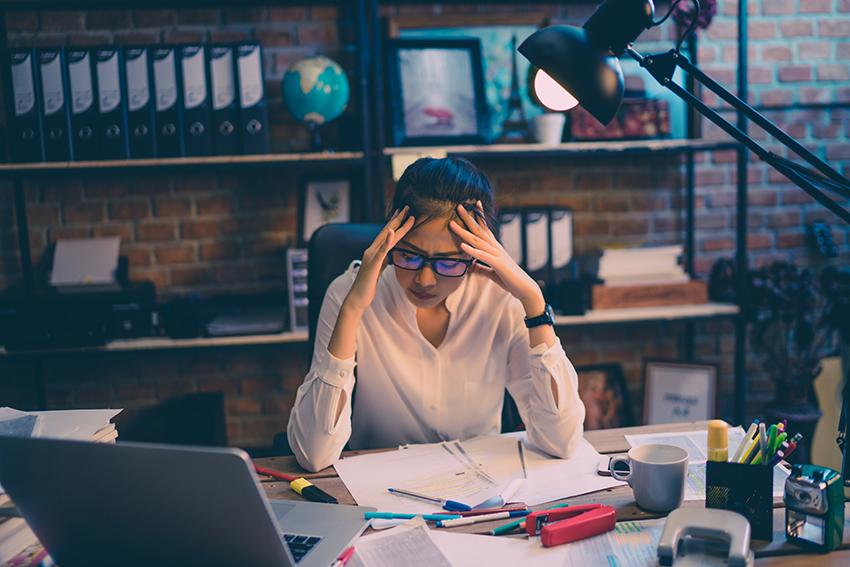 image of woman stressed over paperwork with a laptop for the blog about America's Stress Levels: Exploring Top & Bottom 3 Cities