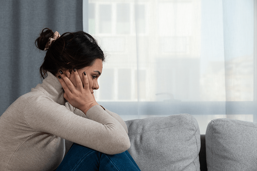 Image of lady sitting on couch with head in hands. Hero image for How to Stop Overthinking and 8 Recommended CBD Products to Try blog