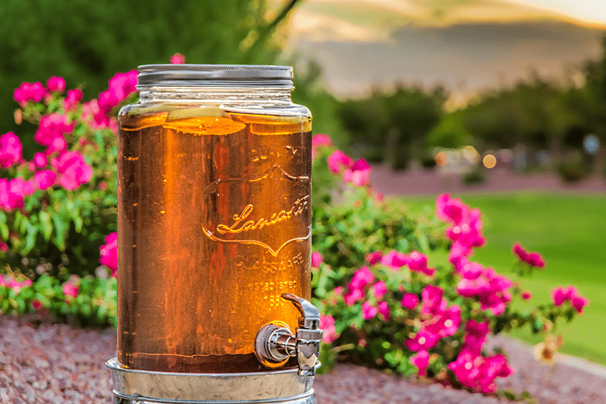 Image of a tea pitcher in front of spring florals. For our blog titled Sip on Sunshine: How to Make Sun Tea