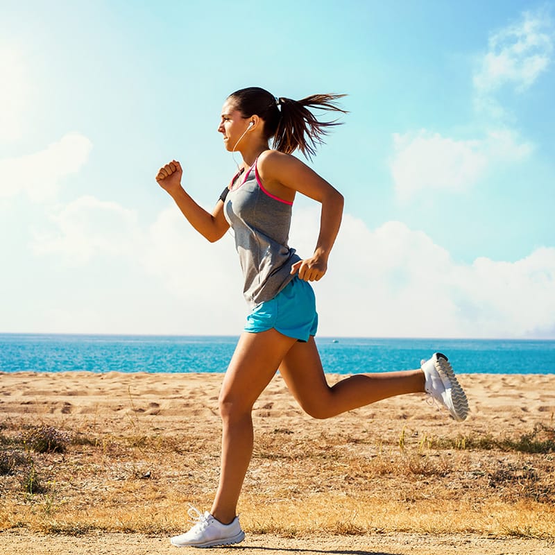 image of a girl with energy running on a beach in front of water