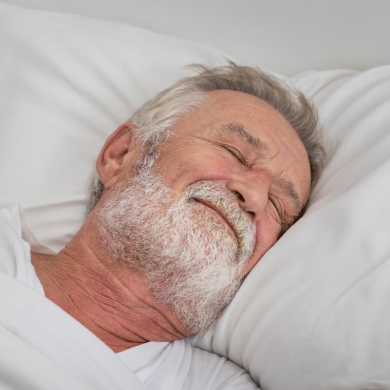 Senior elderly man sleeping peacefully with white blanket in bedroom