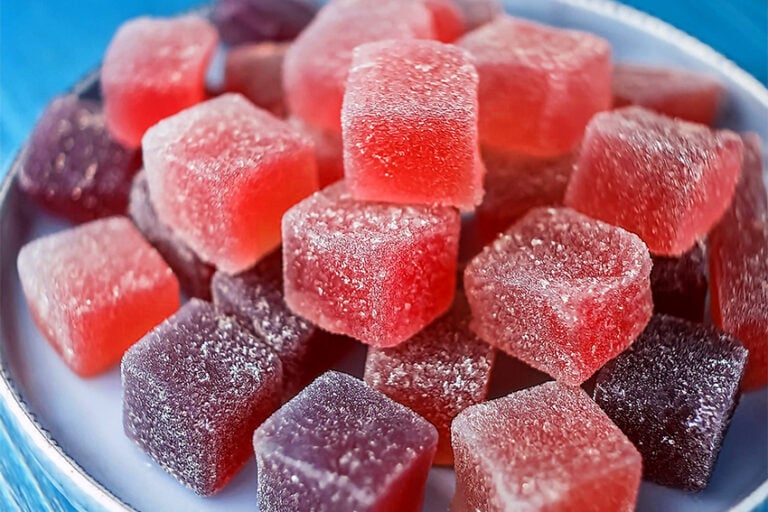 Sugar-free CBD gummies in various flavors including blackberry hibiscus, strawberry, and mixed berry arranged on a white plate, zero sugar hemp extract edibles
